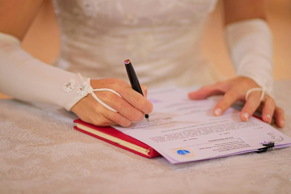 Close-up of a bride signing her wedding certificate at a ceremony.